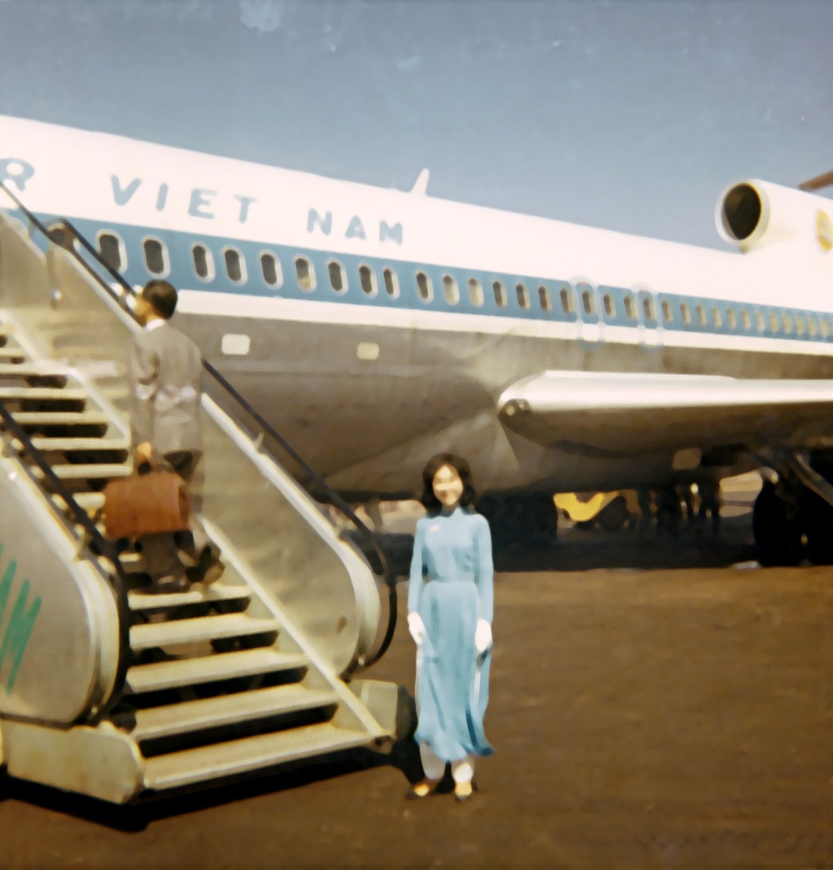 1968 Saigon, Vietnam, an Air Vietnam Flight Attendant welcomes passengers aboard a Boeing 727-100 leased from Pan Am.